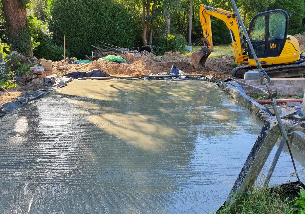 A concrete foundation being poured in a backyard.